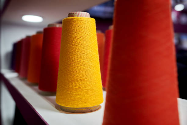 Side view of red & orange cotton yarn spindles.