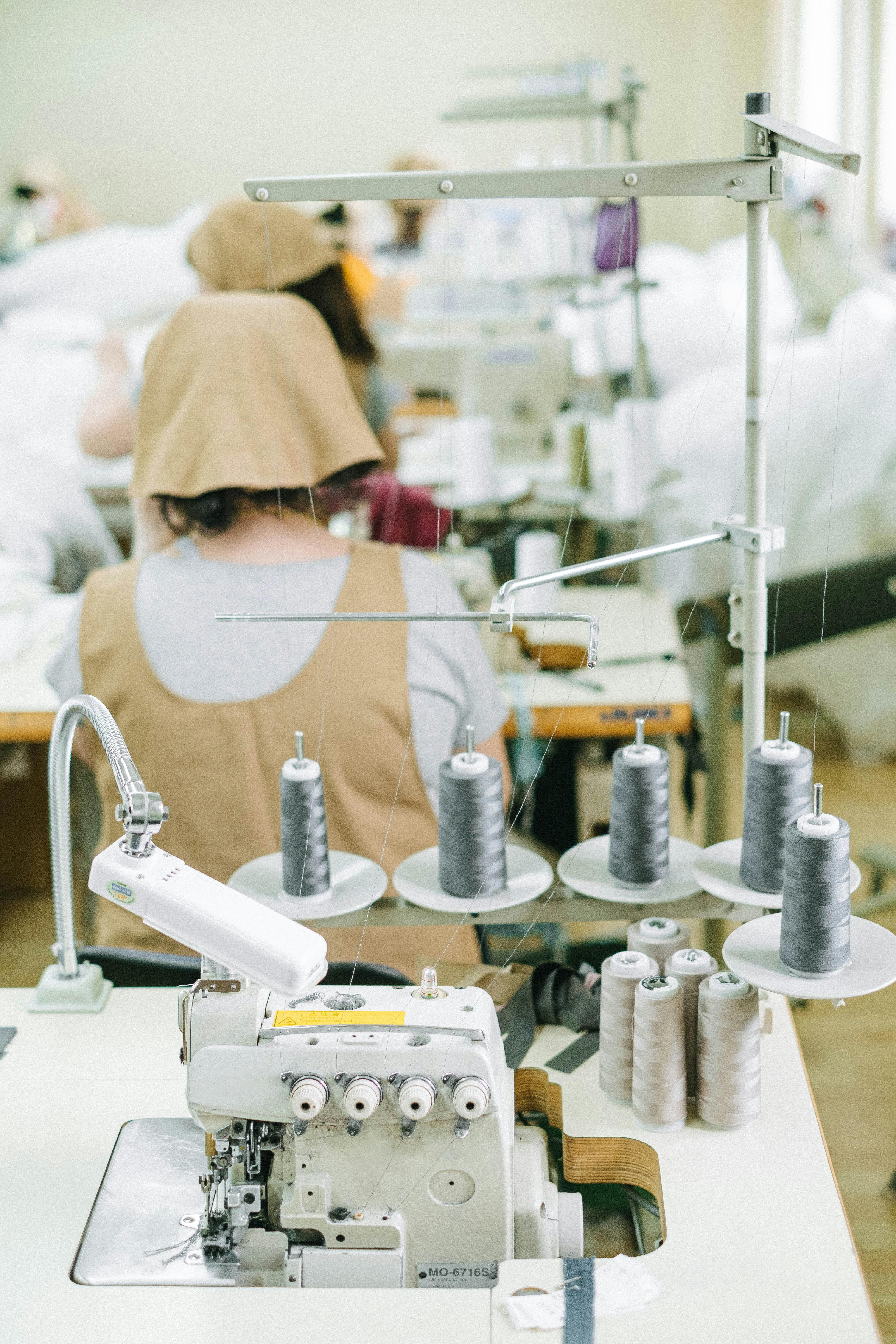 pexels-photo-4492087-4492087 Sewing machines and workers in a textile factory, highlighting industrial manufacturing processes.