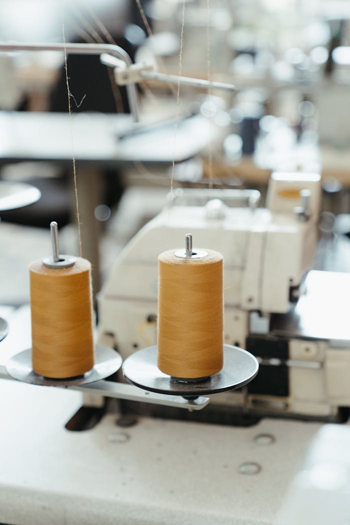 Detailed view of a sewing machine with spools of thread in a workshop setting.