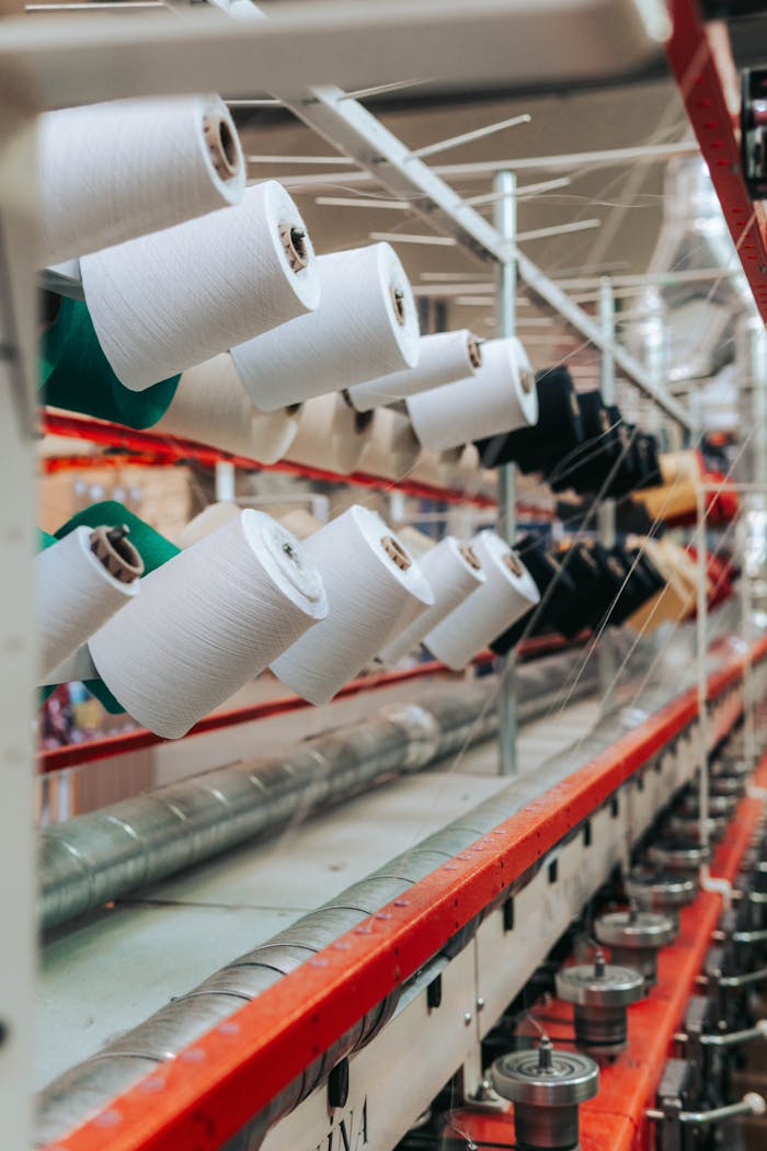 pexels-photo-6717035 Detailed view of yarn spools in a textile factory, showcasing industrial equipment.