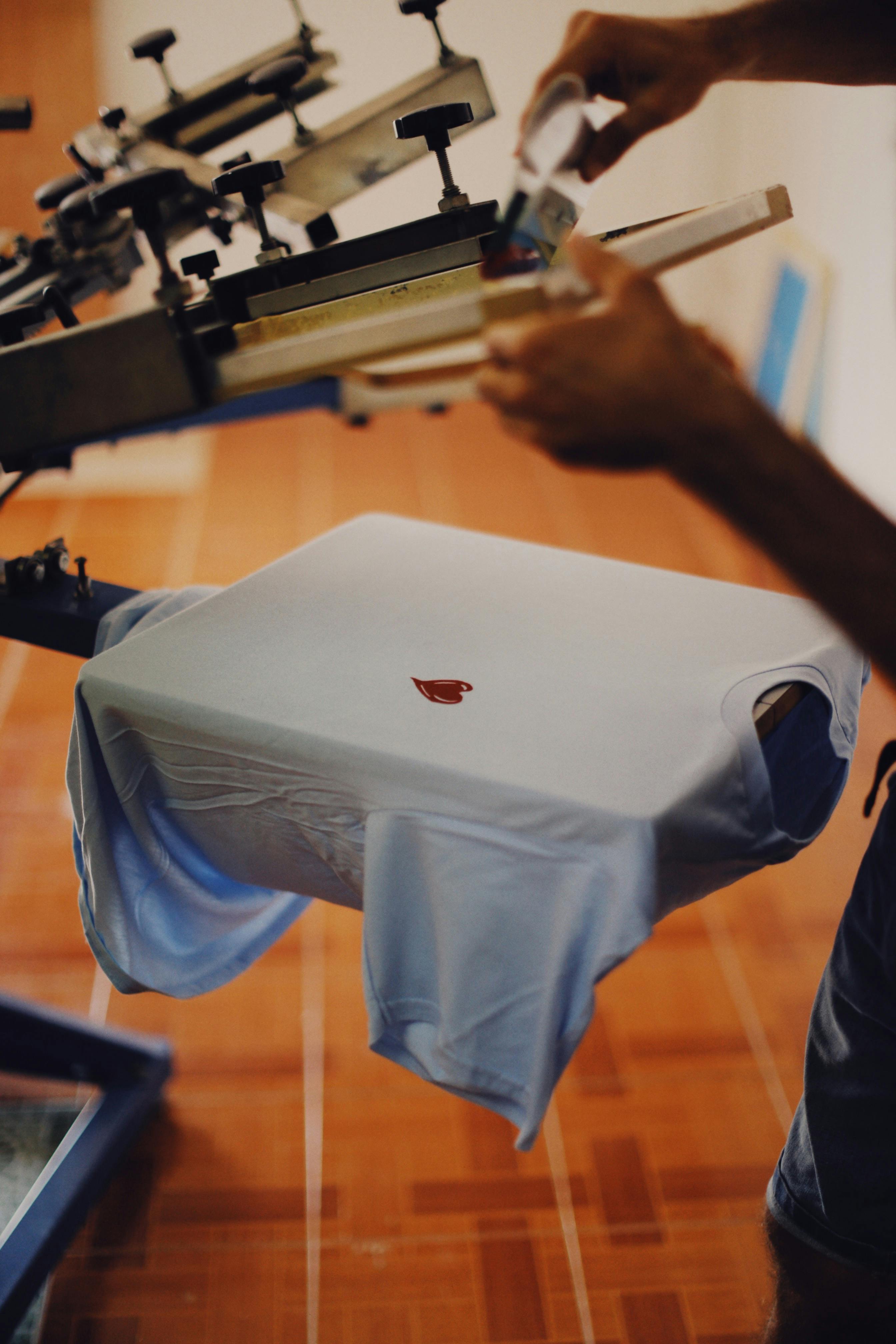 pexels-photo-9314012-9314012 Close-up of a man using a T-shirt printing machine indoors.