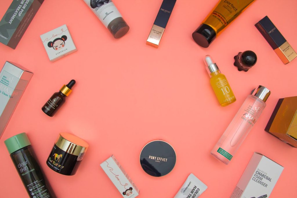 Assorted skincare and beauty products in flat lay on a vibrant pink backdrop.