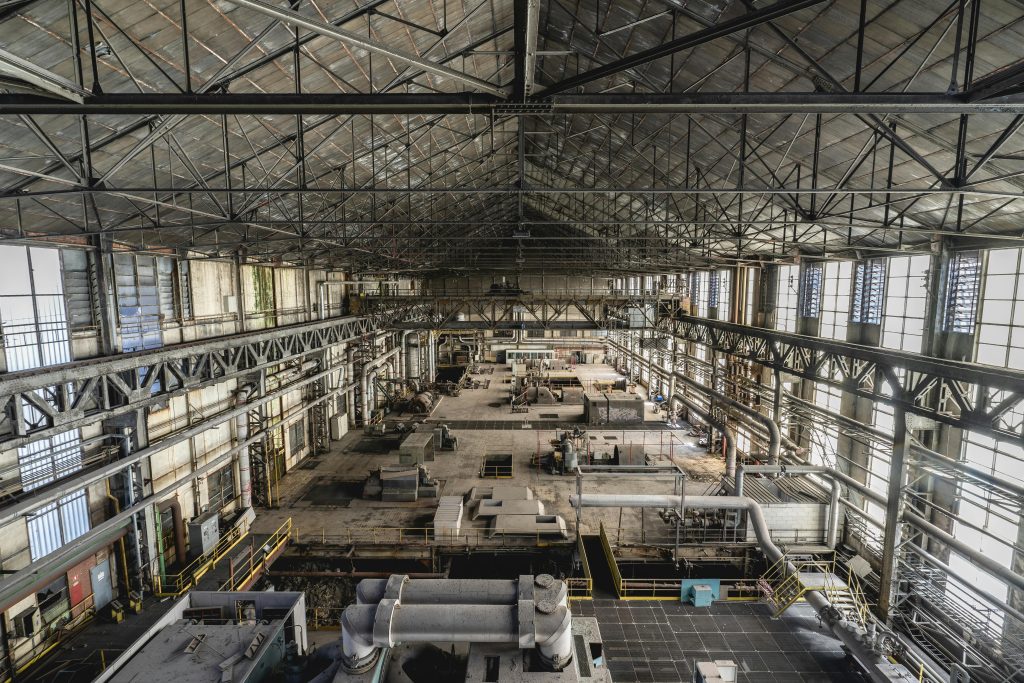 A wide-angle view of a spacious industrial warehouse interior with steel structures and machinery.