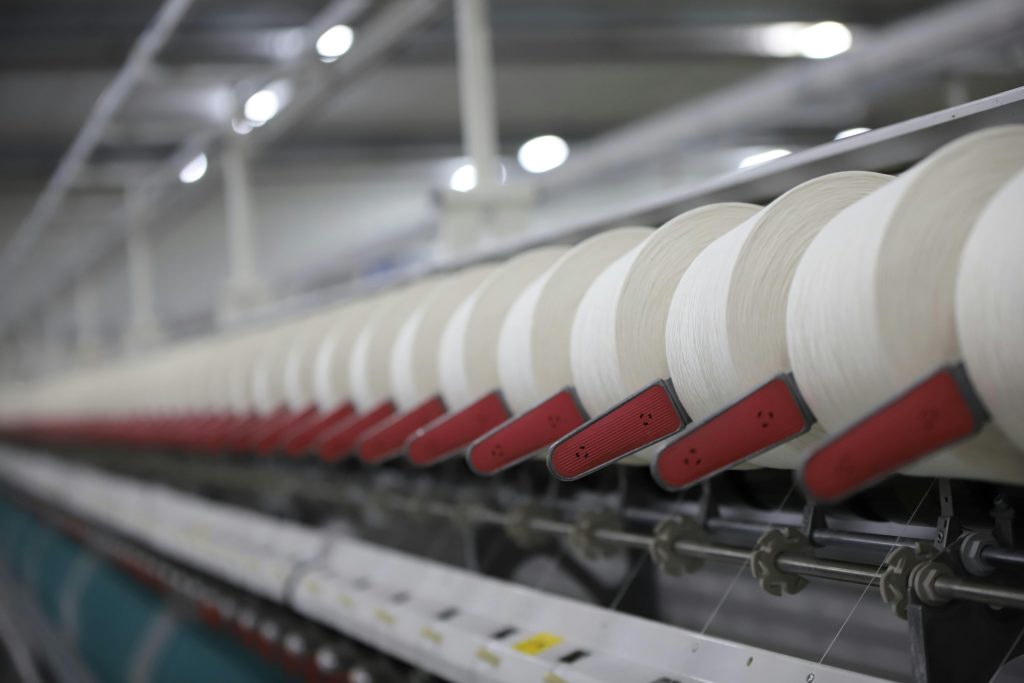 Close-up view of a textile production line showcasing white thread spools in an Indian factory.